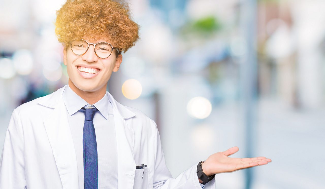 Young male scientist wearing glasses smiling cheerful presenting