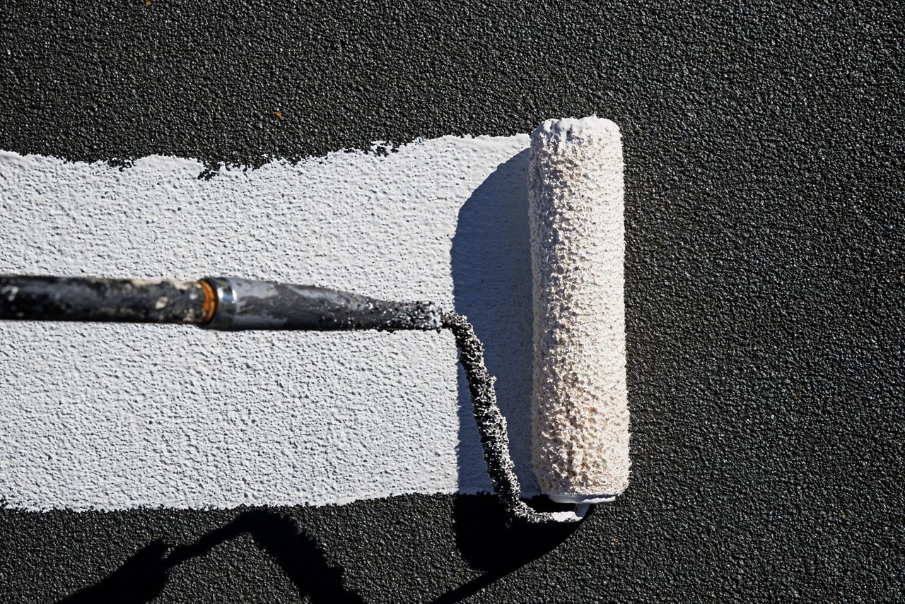 Roof coating being spread with a roller 