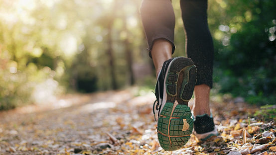 自然界中跑步的人的跑步鞋的特写，并有漂亮的阳光 