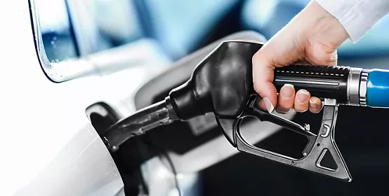 Woman pumping petrol at gas station into vehicle. Hand holding a pistol or nozzle pump prepare to refuel car with gasoline.