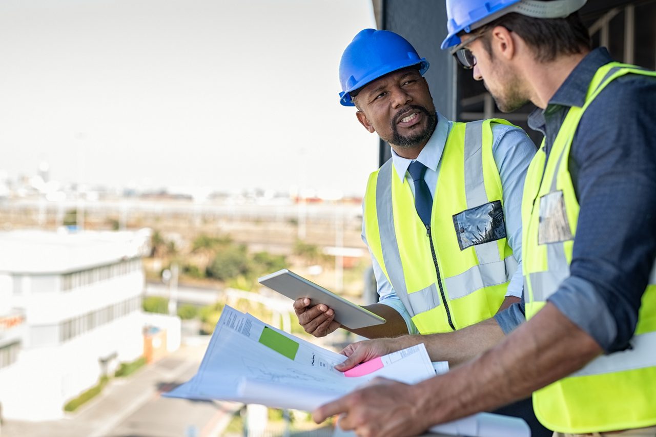 Construction workers talking while holding blueprints