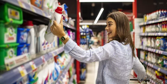 Pretty young woman buying groceries in a supermarket/mall/grocery store. Beautiful brunette looking at some shelves in a supermarket trying to decide what to buy