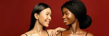 African and Asian women posing together and smiling