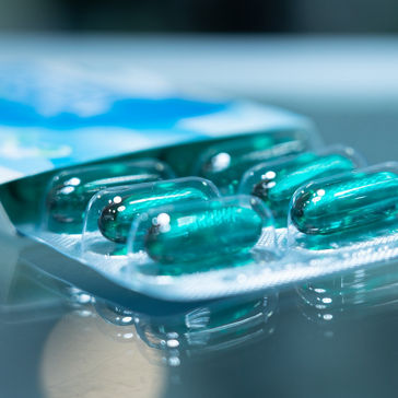 Medicamento em cápsula de gel mole azul em embalagem de tiras com fundo desfocado