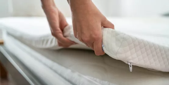 Mattress Topper Being Laid On Top Of The Bed