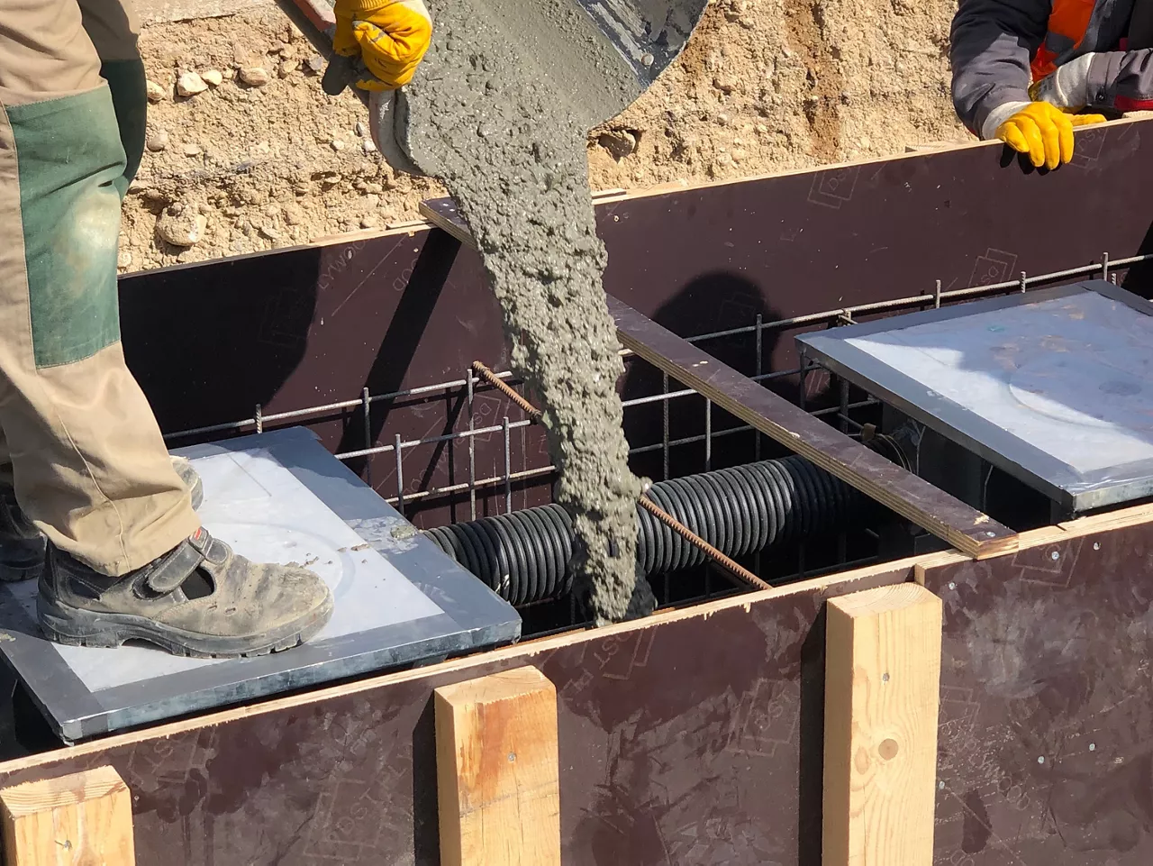 Construction workers are pooring concrete to formwork.