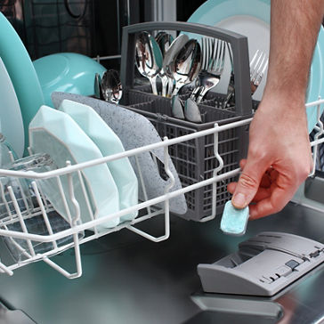 Um homem coloca o comprimido na lava-louças para lavar pratos sujos