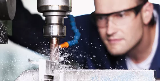 Close up of worker with safety glasses at milling machine in workshop.