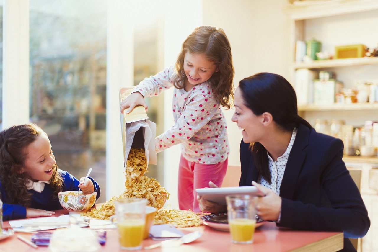 Girl pouring abundance of cereal at breakfast table