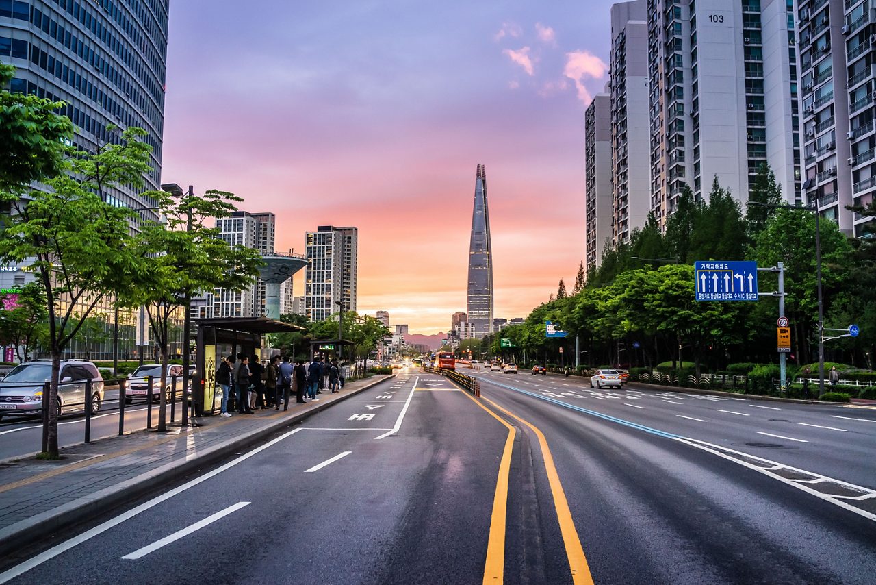 Carretera de la ciudad con cielo rosa y edificios altos en el horizonte