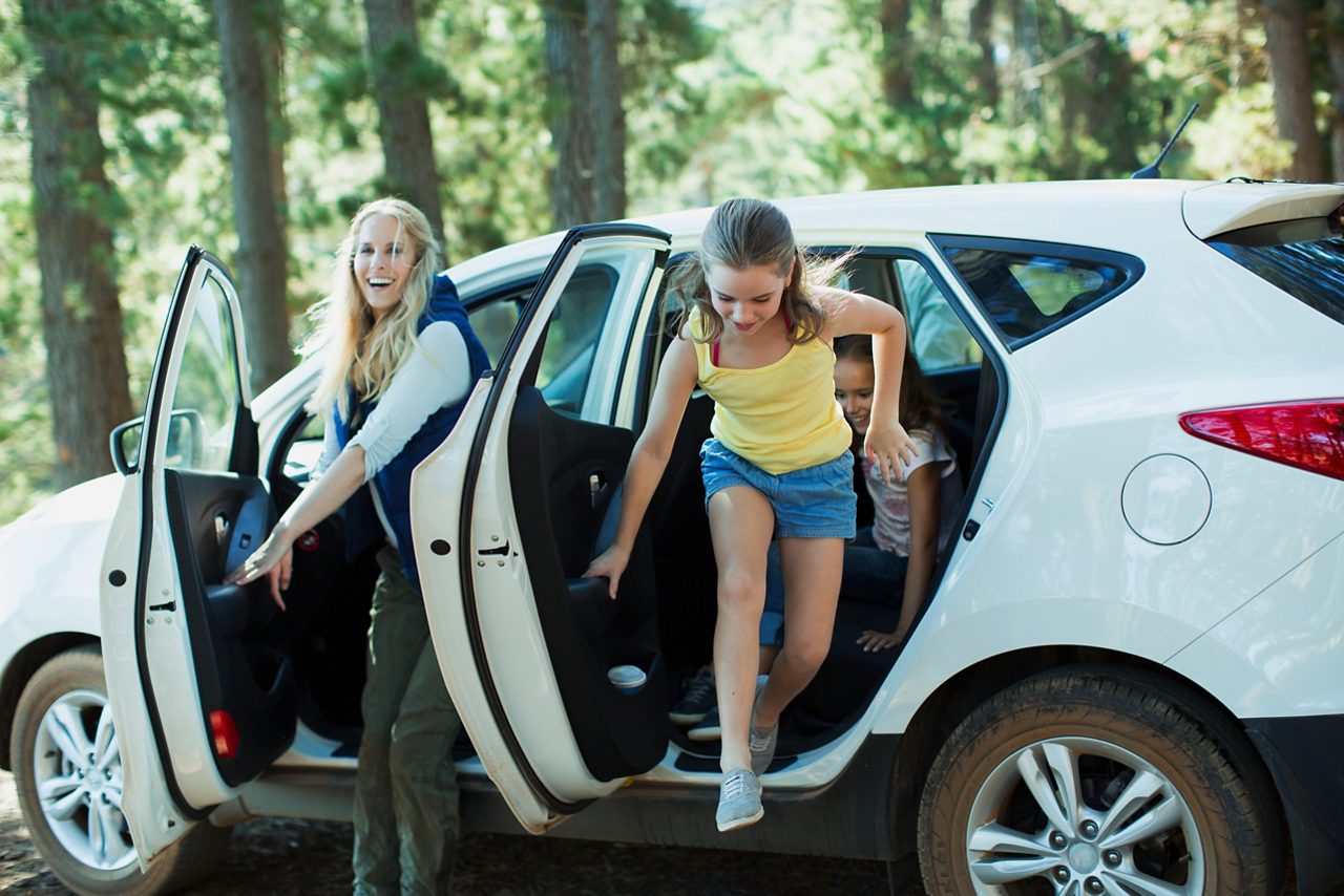 Mother and daughters getting out of car in woods