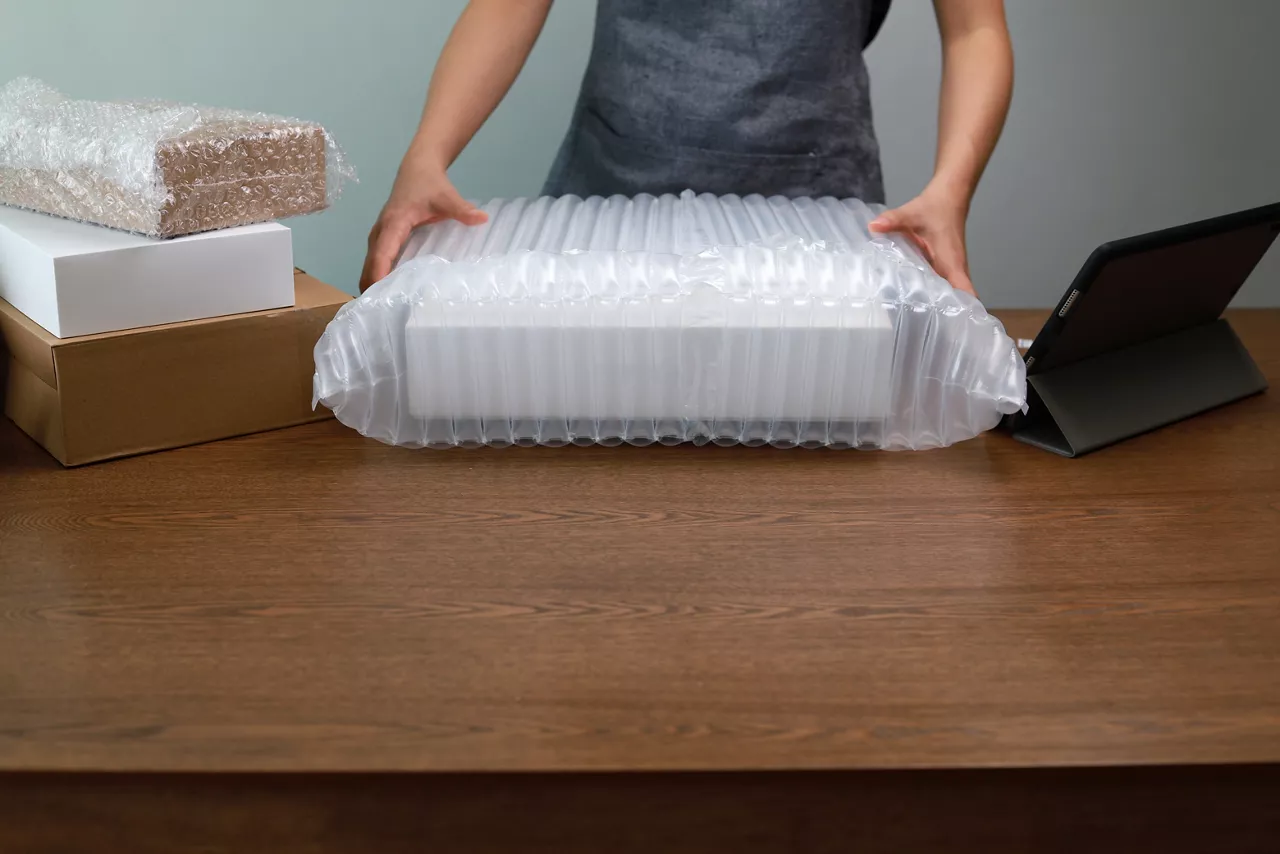 Person using an inflatable air pillow to protection a packaging for shipping