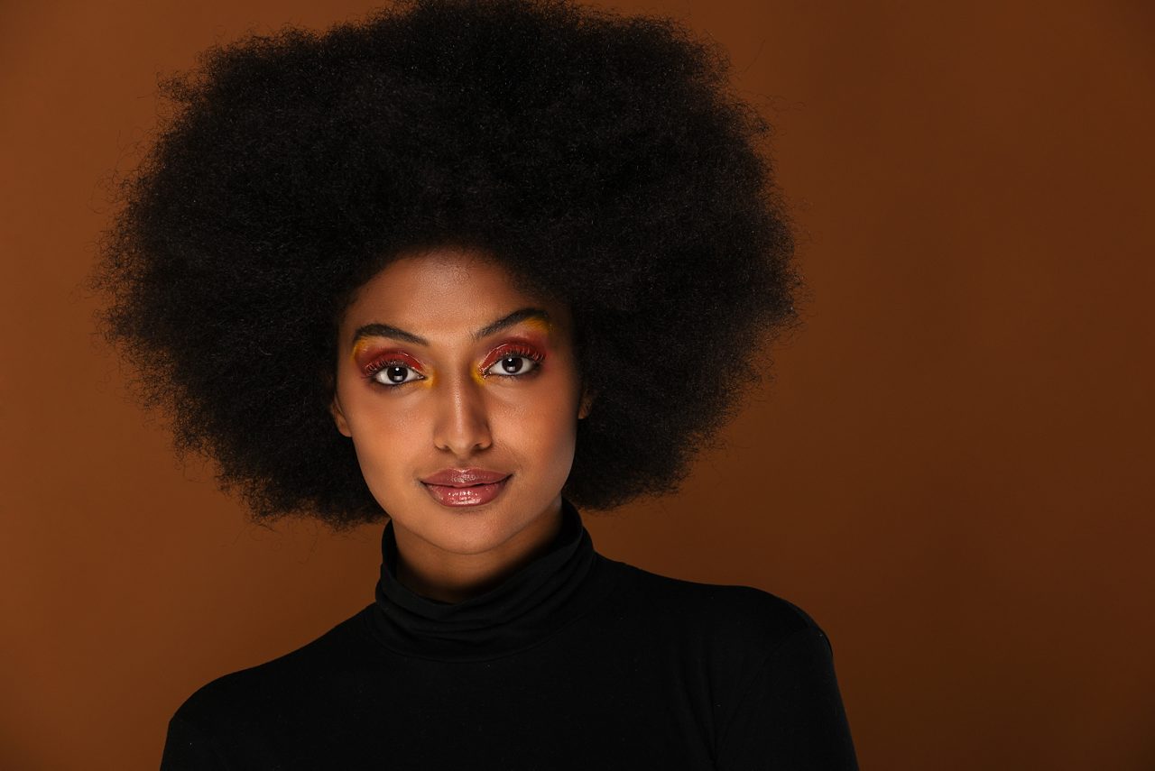 Portrait of pretty afro American woman in a studio for a beauty session - Beautiful girl posing on colored background.