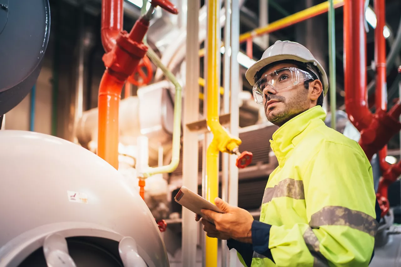 Safety Officer checking machine giant motor Modern Industrial food freeze Manufacturing Factory. Large Industry Caucasian white wearing safety vest take note maintenance of machines in the factory.