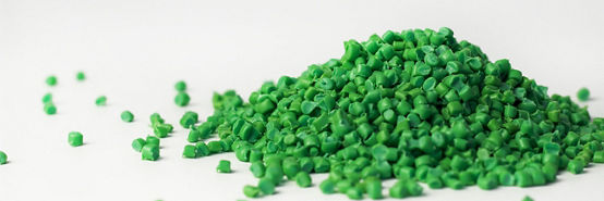 Green granules of polypropylene or polyamide on a white background. Plastics and polymers industry. Copy space.