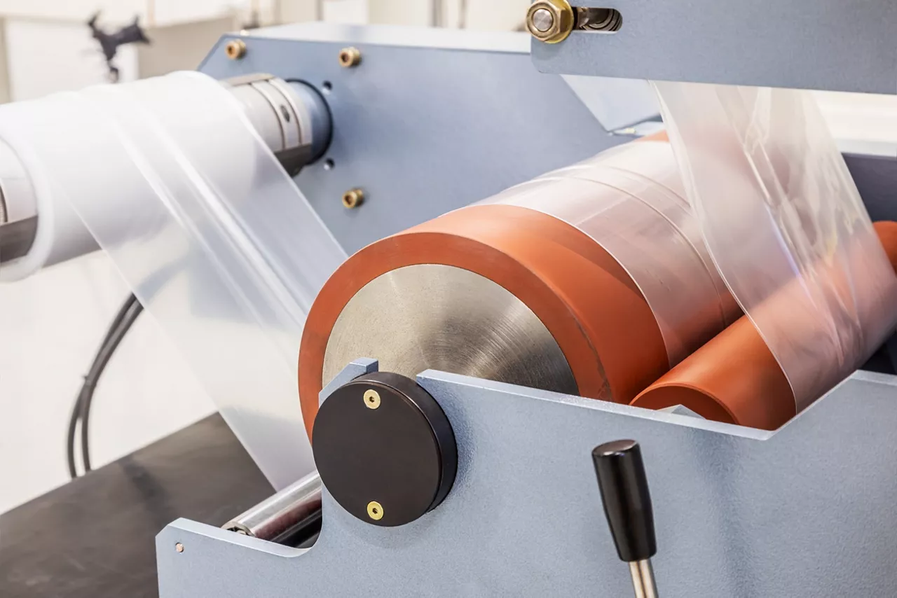 Industrial machine with roll of newly produced transparent plastic film