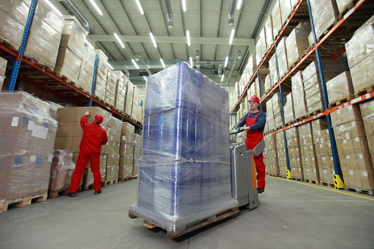 Trabajador de depósito moviendo una paleta de bienes.