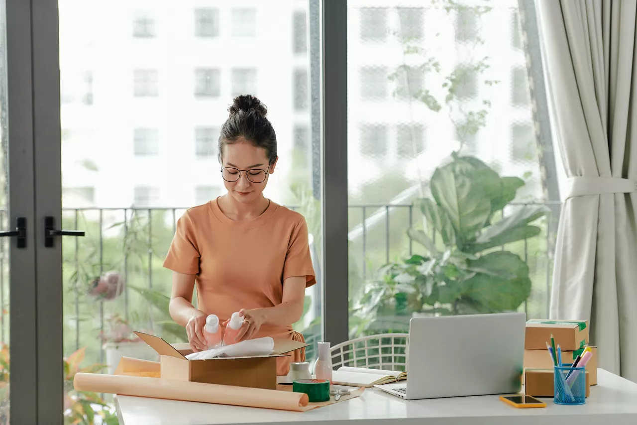 Woman preparing parcels for e-commerce shipment with rigid packaging