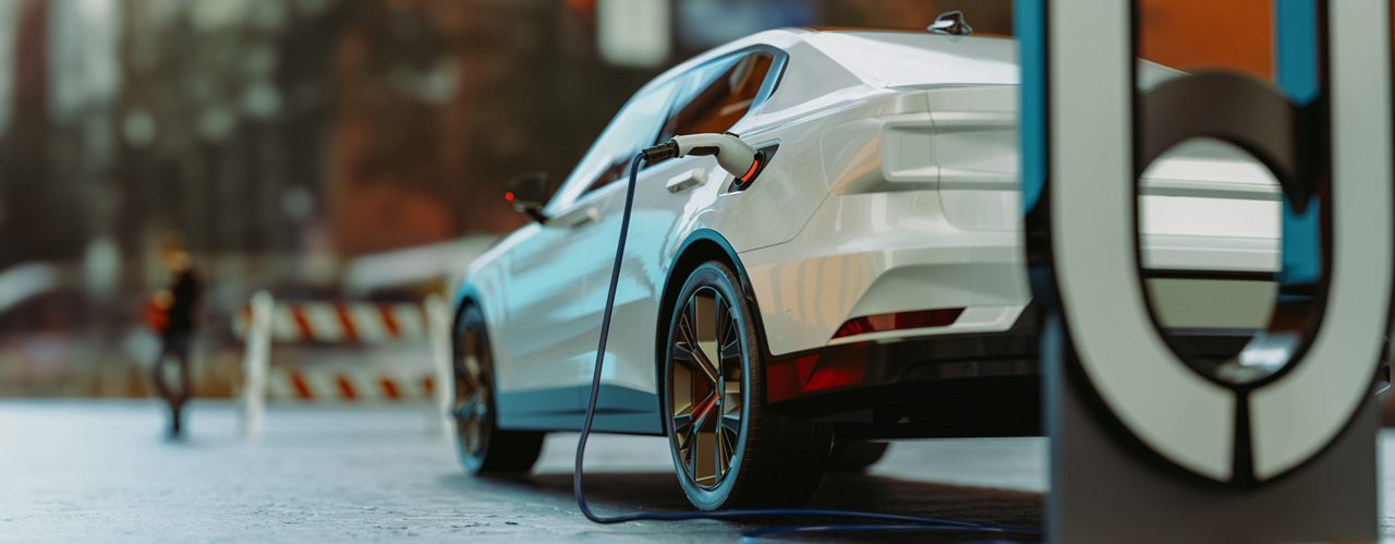 Modern white car plugged in at charging station