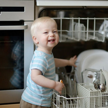 Menino ajudando a remover pratos da máquina de lavar louça