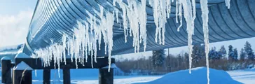 Icicles on a pipe outside in the middle of a winter day 