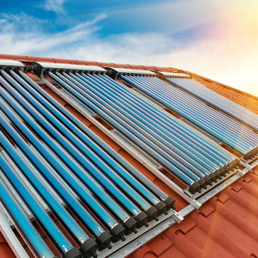 Colectores de vacío: sistema de calefacción solar de agua en el techo rojo de la casa