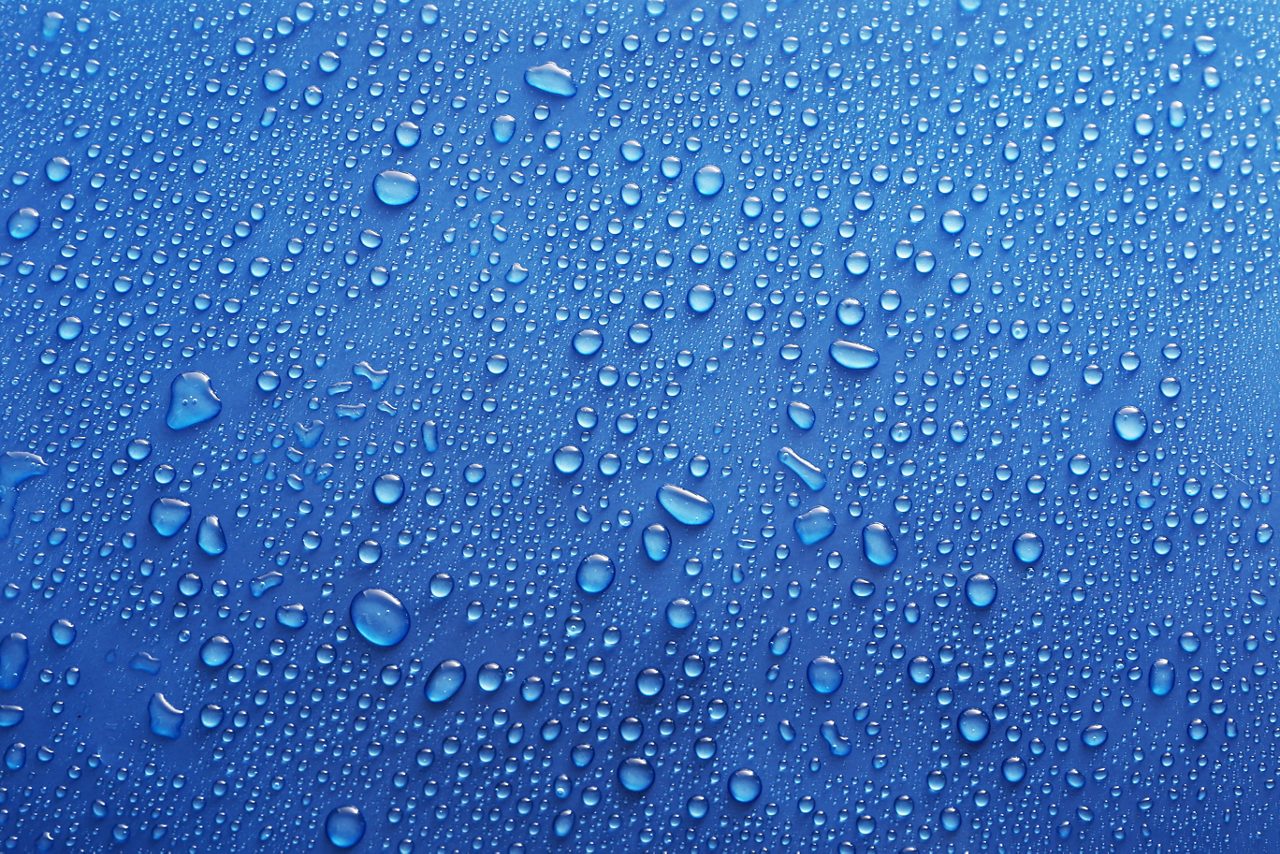 Water drops on glass on blue background.