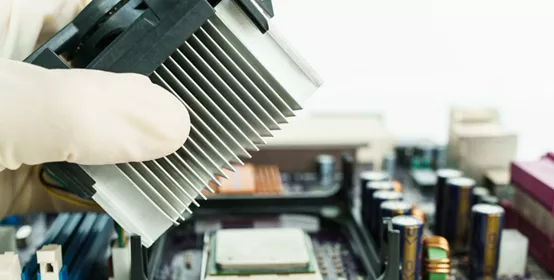 Hand removing heat-sink from mainboard, close-up.