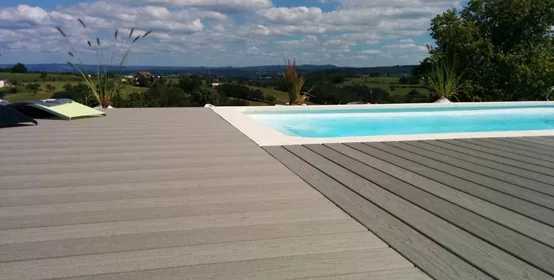 Gray wood composite deck with negative edge pool and sunny blue sky with white clouds in background