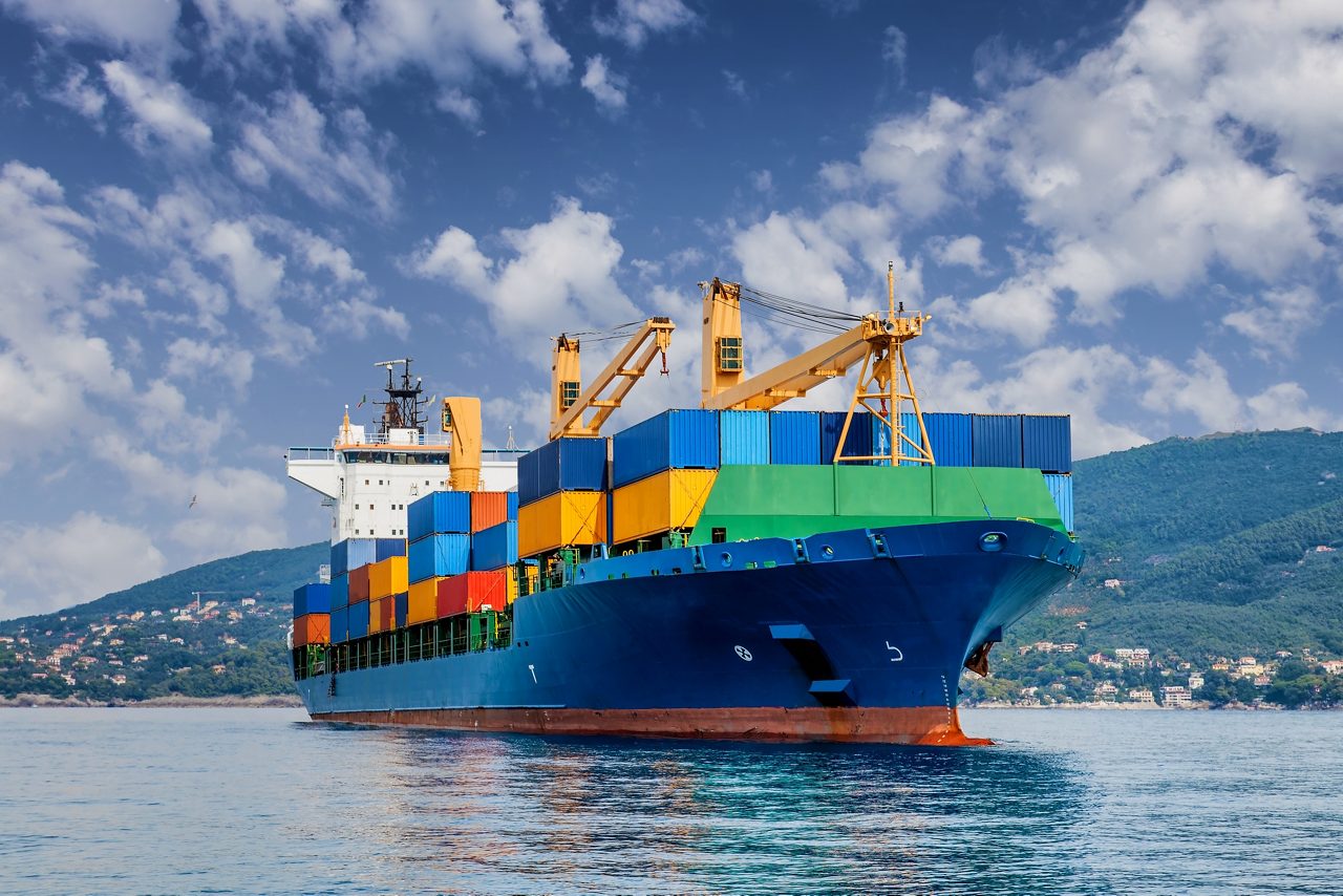 Bow view of loaded cargo ship sailing out of port