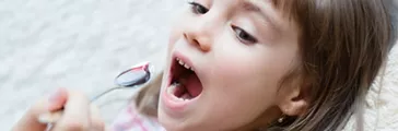 Little girl taking liquid medicine