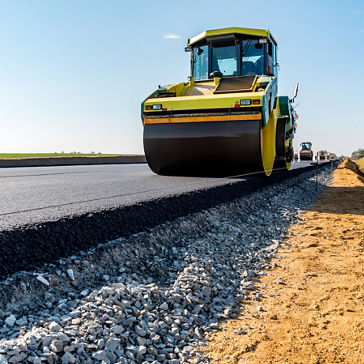 Rodillos de carreteras que construyen la nueva carretera de asfalto