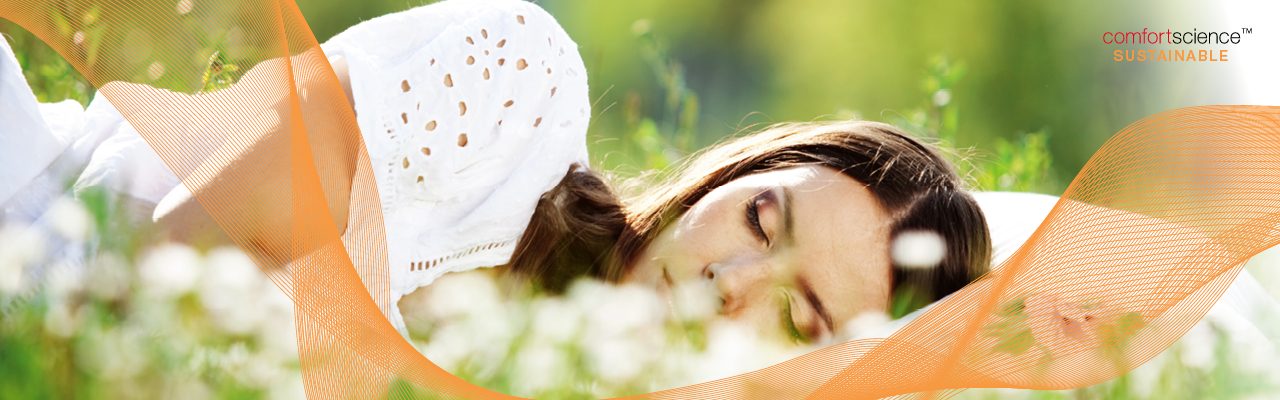 Woman lying with pillow in grass field, ComfortScience Sustainable branding elements 