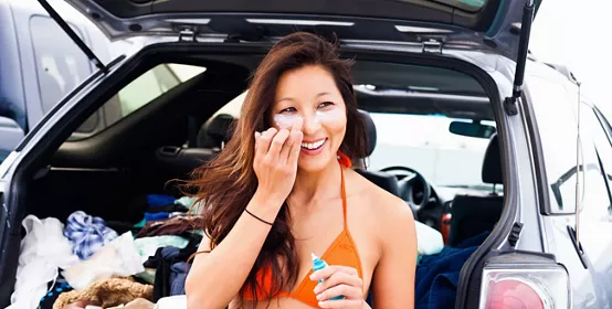 Woman putting on sun cream, Hermosa Beach, California, USA