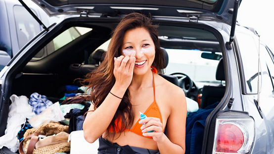 Woman putting on sun cream, Hermosa Beach, California, USA