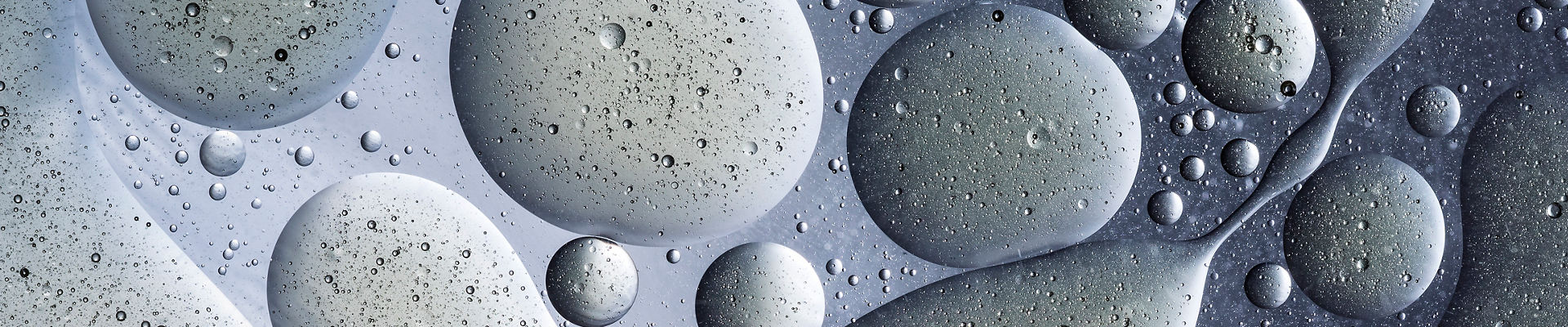 Full frame of the textures formed by the bubbles and drops of oil in the shape of circle floating on a gray and yellow colors background
