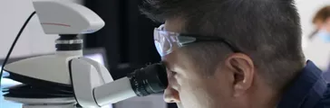Dell Doyle looking through a microscope in a lab.