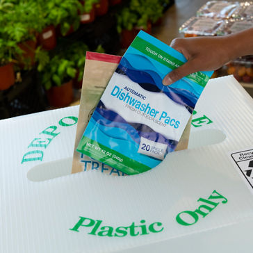 Pessoa que recicla embalagens flexíveis no recipiente de entrega da loja