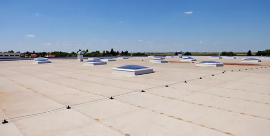 Flat roof with skylight and hydro insulation membranes under a blue sky with few clouds.