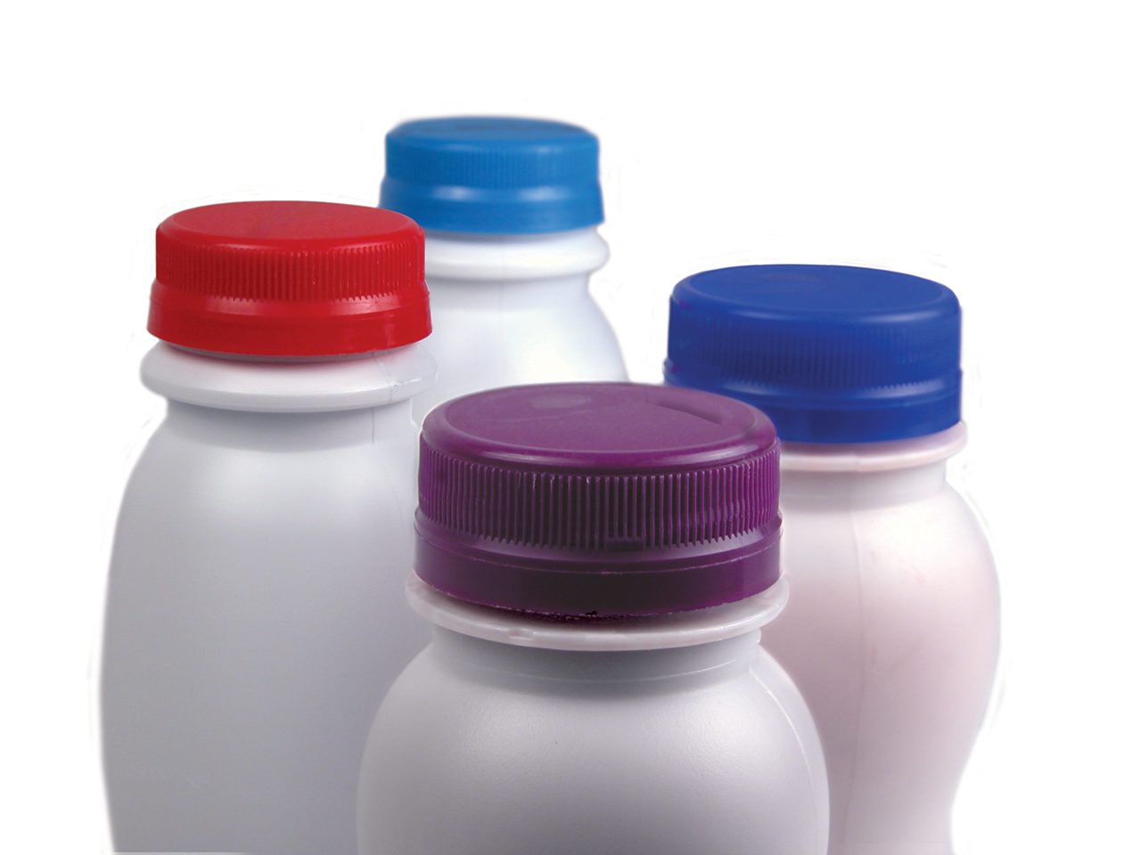 Four single-serve dairy containers with purple, red, light blue and royal blue compression molded closures on white background