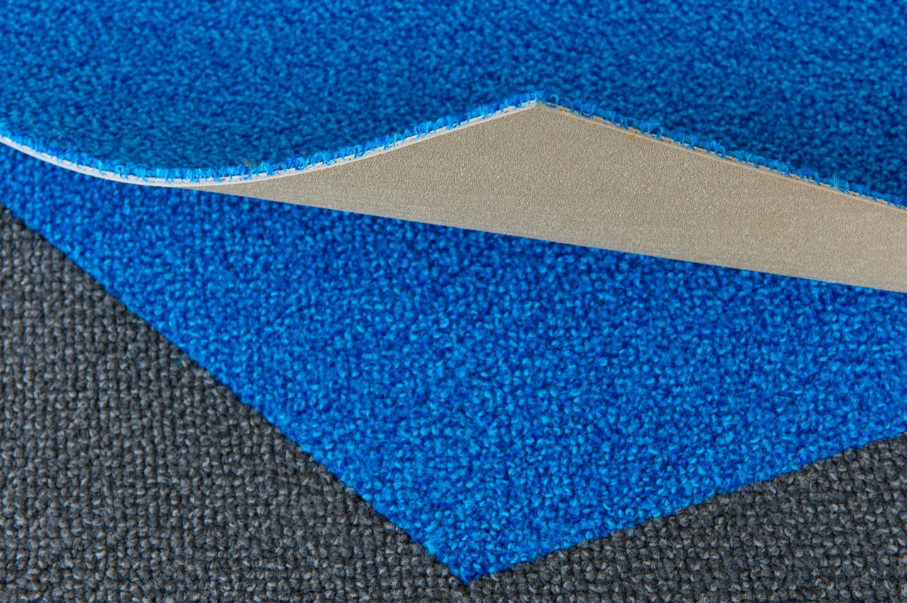 Blue and gray carpet with a piece curled to show the backing 