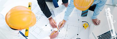 Group of architects and businessmen wearing hard hats and going over building plans