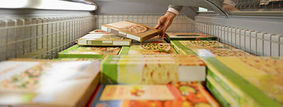 Person selecting a frozen pizza from a freezer case