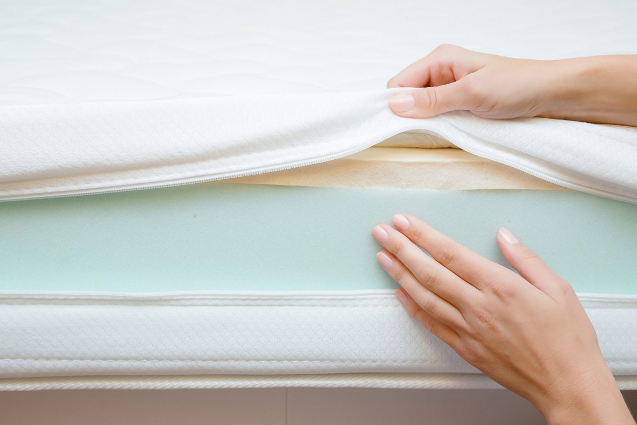 Woman's hands touching different layers of new mattress. Checking hardness and softness. Choice of the best type and quality. Front view. Close up.