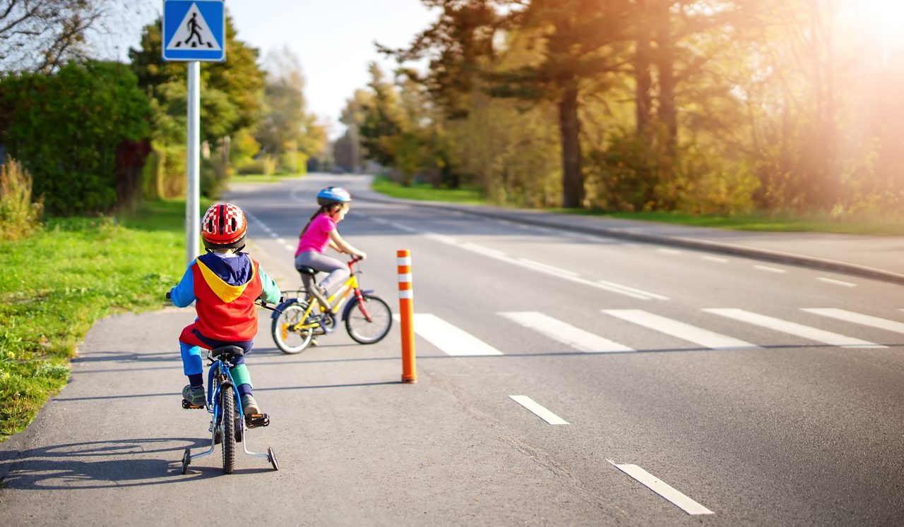 Duas crianças andando de bicicleta na faixa de pedestres