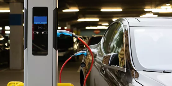 Electric car charging at a charging station in the parking garage of a shopping center