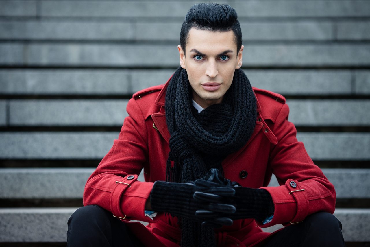 Fashionable androgynous male model posing outdoors in red coat and black scarf; Shutterstock ID 158792045