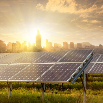 painéis solares e geradores eólicos contra a vista da cidade ao pôr do sol
