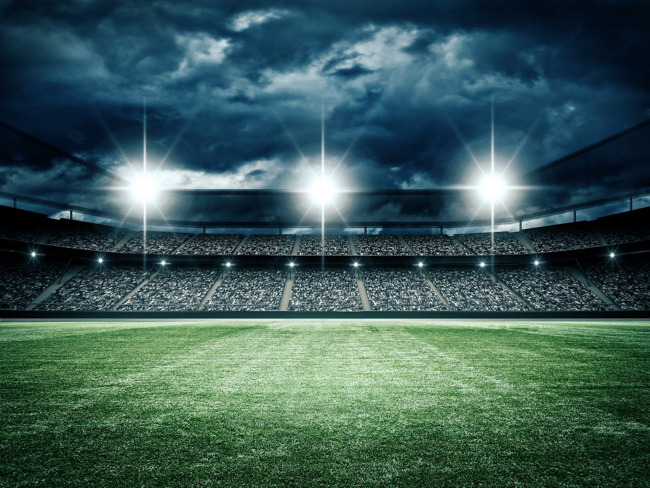 View from the ground looking up at the lights of a stadium on a cloudy night.