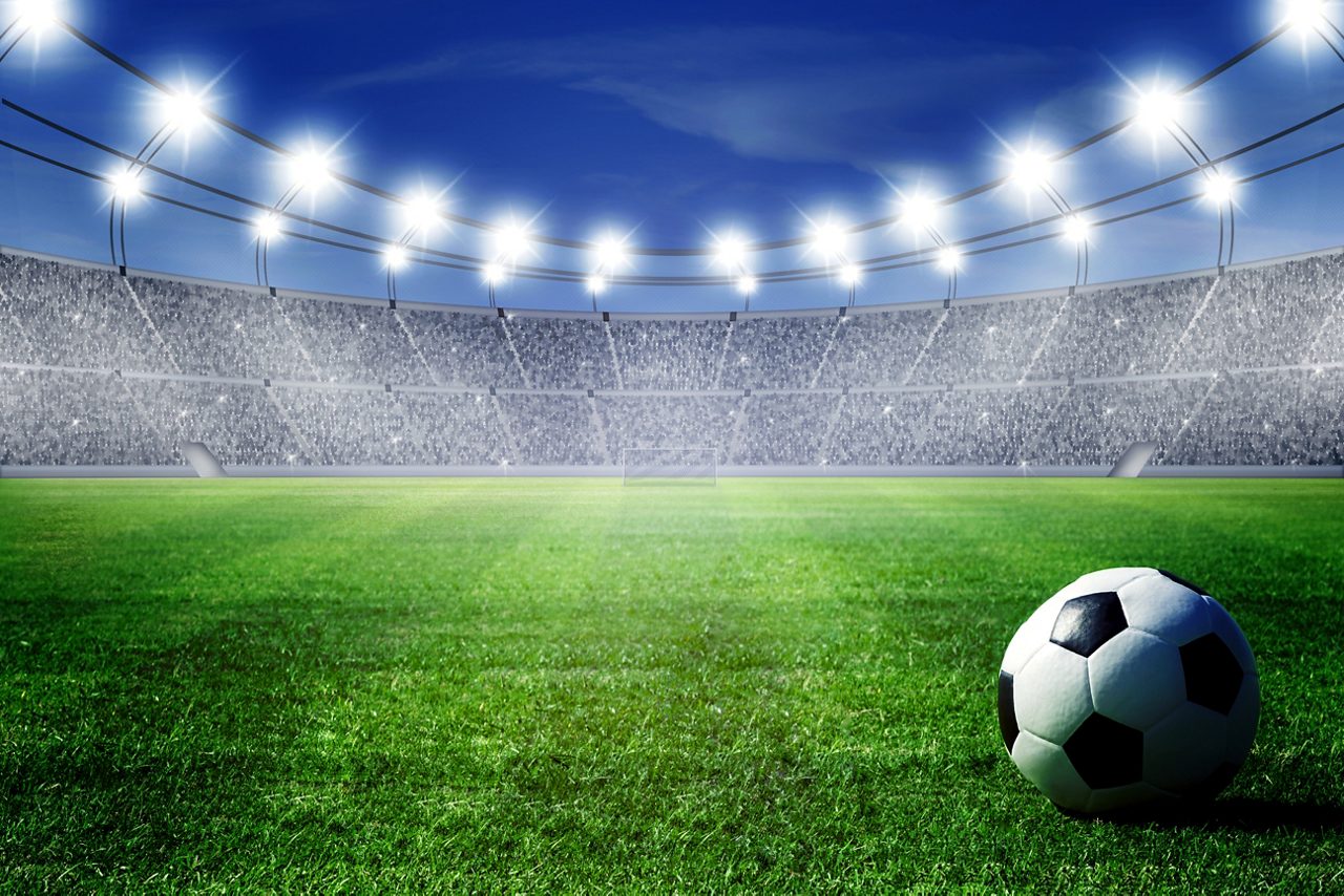 Soccer ball on field of filled and lighted stadium